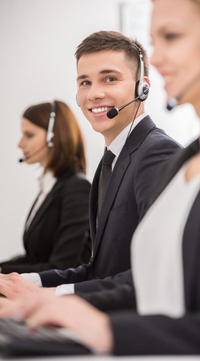 Line of phone operators with headsets work at office.